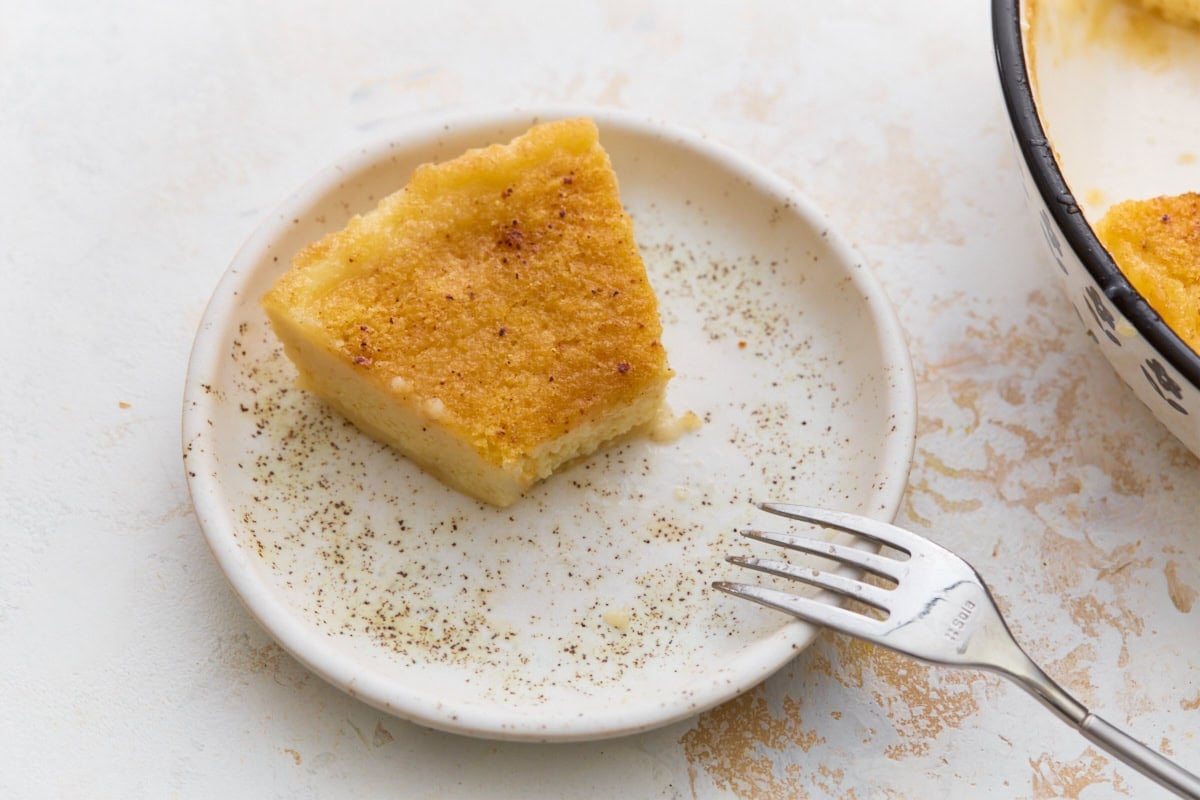 Slice of creamy crustless custard pie served on a plate with ground nutmeg and a fork