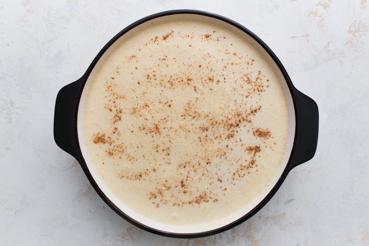 Unbaked crustless custard pie filling sprinkled with nutmeg in a pie dish
