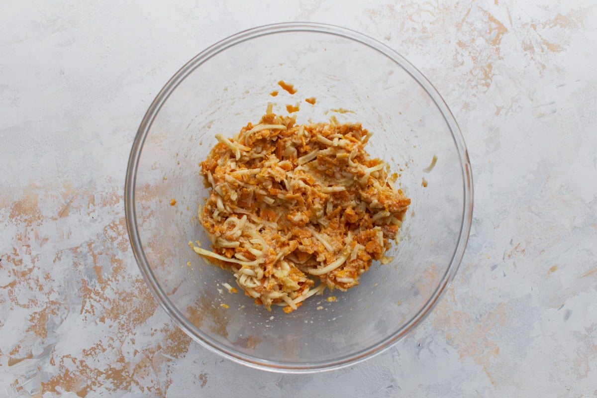 Cheese and egg mixture combined in a glass bowl for crustless tomato pie filling.