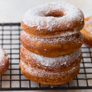 Stack of gluten-free mochi donuts dusted with powdered sugar on a cooling rack