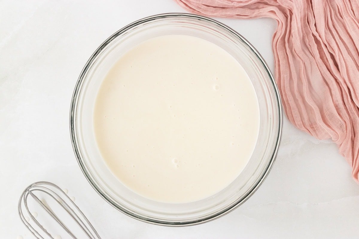 Smooth coconut sorbet mixture in a glass bowl after whisking together the ingredients.