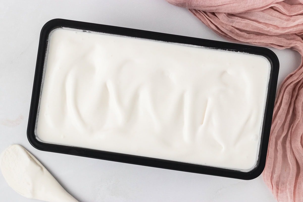 Homemade coconut sorbet spread evenly into a loaf pan after freezing.