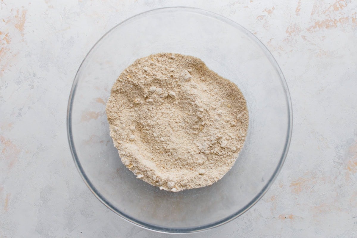 Dry oat flour waffle ingredients mixed together in a glass bowl.