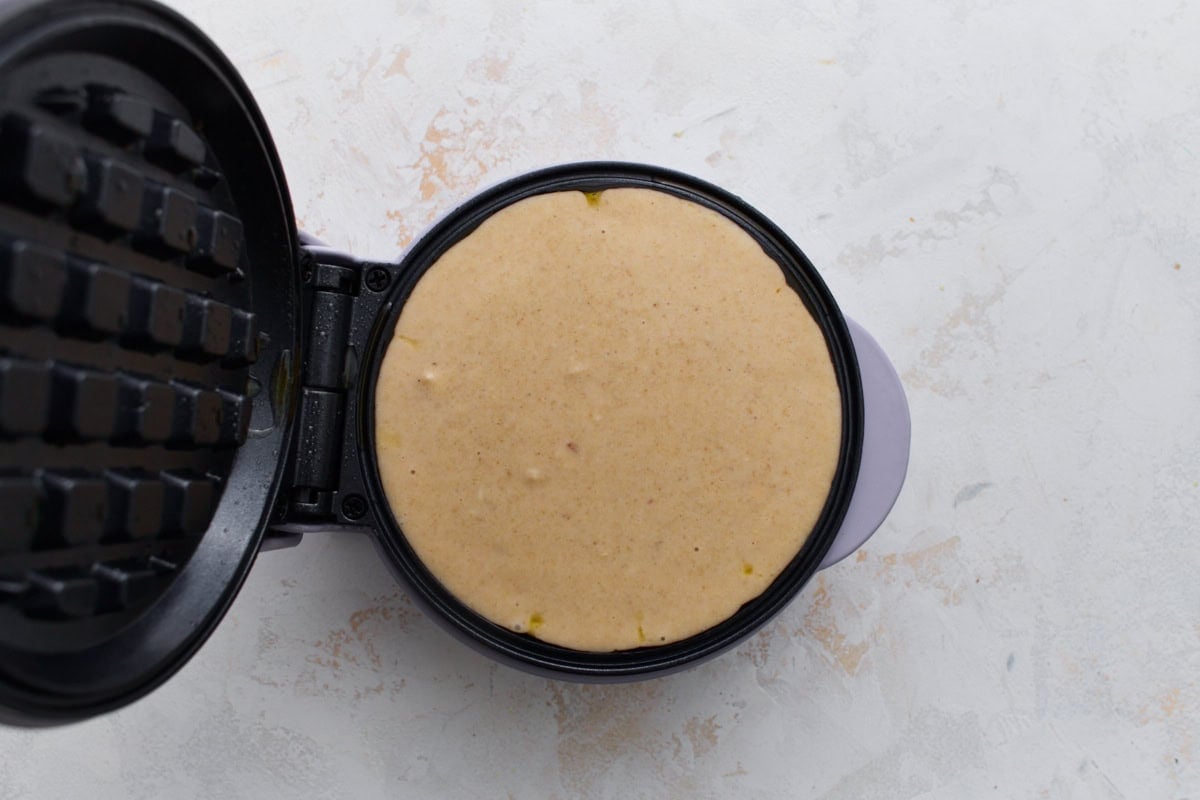 Oat flour waffle batter poured into a waffle maker before cooking.