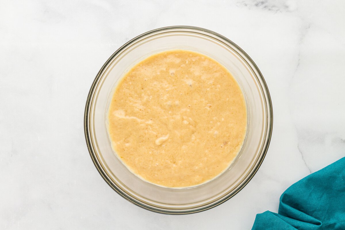 Gluten-free vanilla cake donut batter partially mixed in a glass bowl.