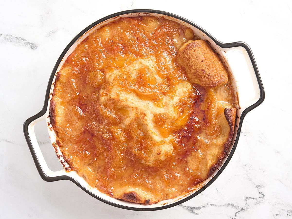 Freshly baked gluten free peach cobbler with a deep golden brown top and bubbling peach filling around the edges