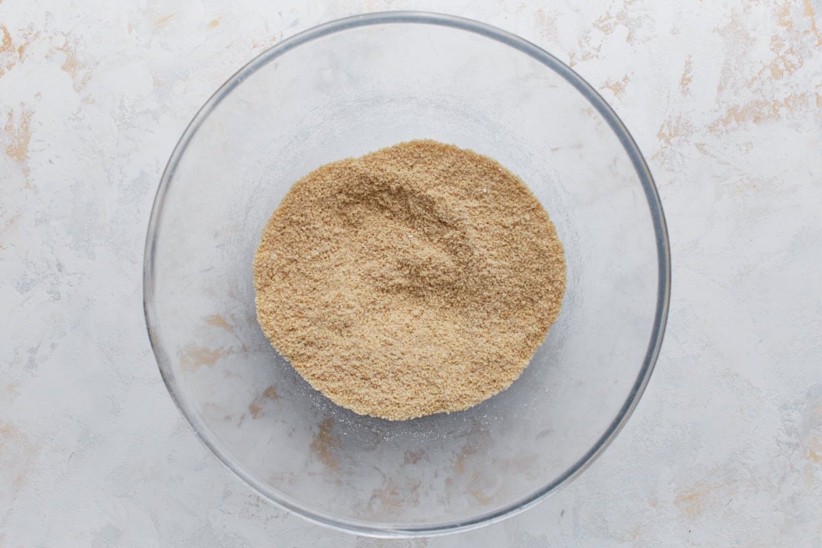 Overhead view of almond flour and dry ingredients combined in a glass mixing bowl