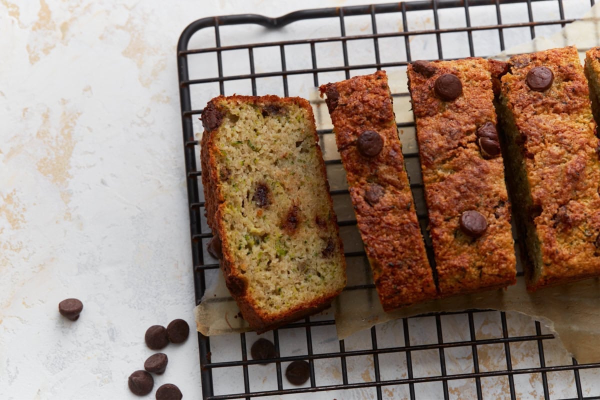 Close up of sliced almond flour zucchini bread with chocolate chips on a black wire rack with chocolate chips scattered around