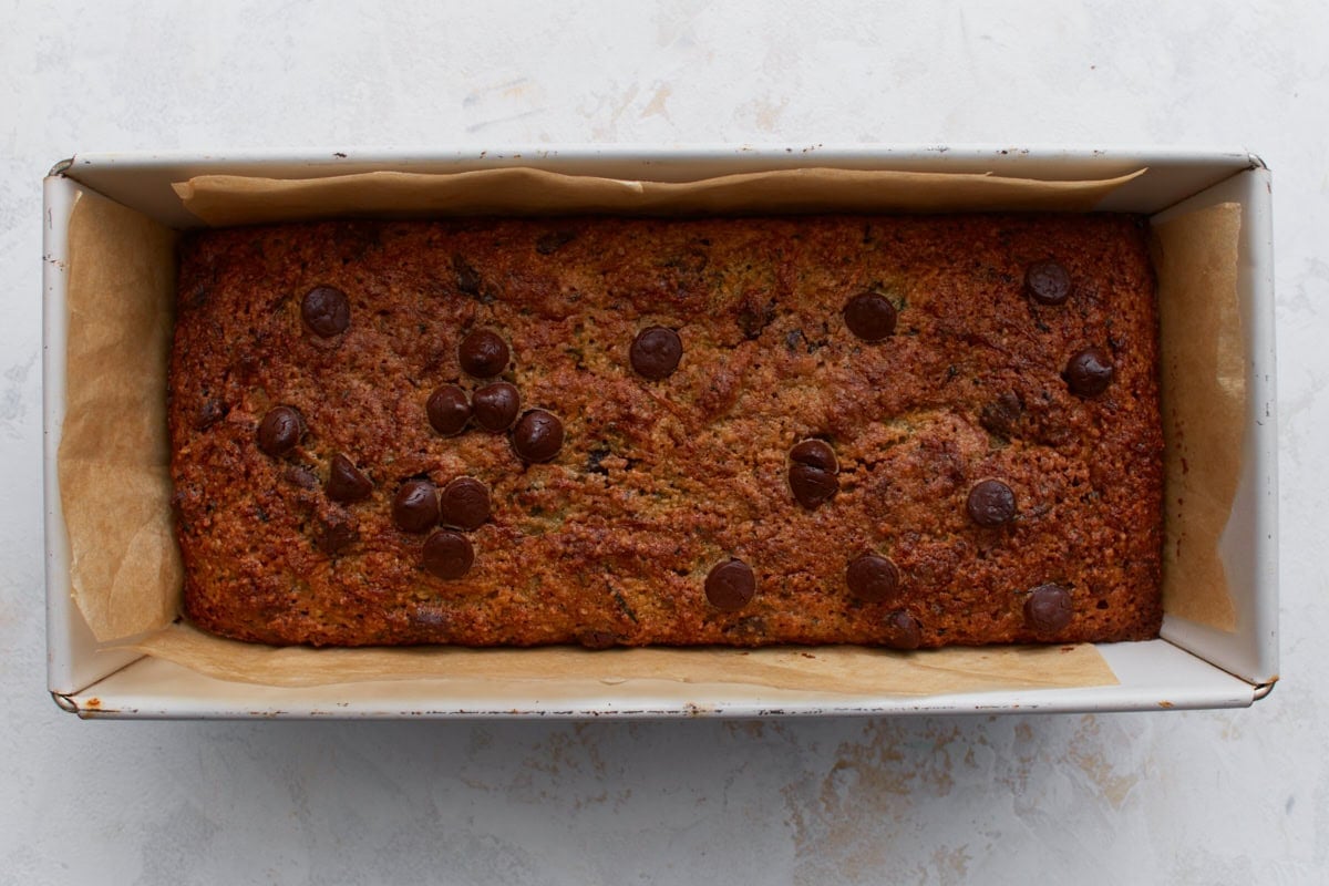 Freshly baked almond flour zucchini bread with chocolate chips in a parchment lined loaf pan