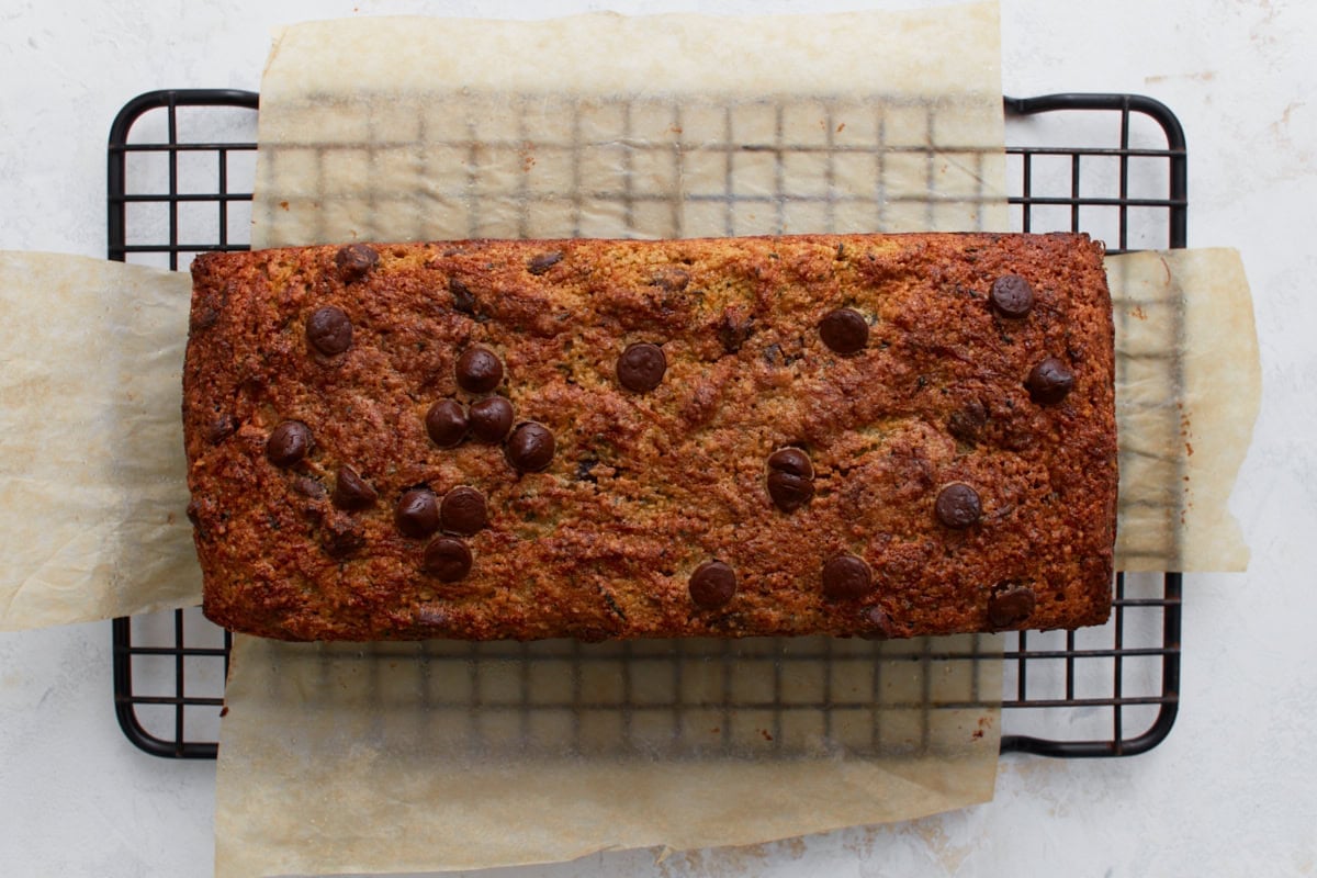 Baked almond flour zucchini chocolate chip bread cooling on a black wire rack on parchment paper