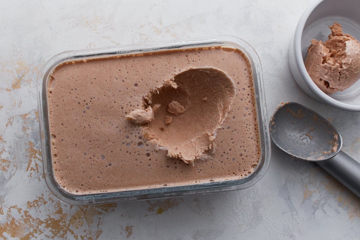 Scoop of date ice cream lifted from a freezer-safe container, showing the smooth, creamy texture.