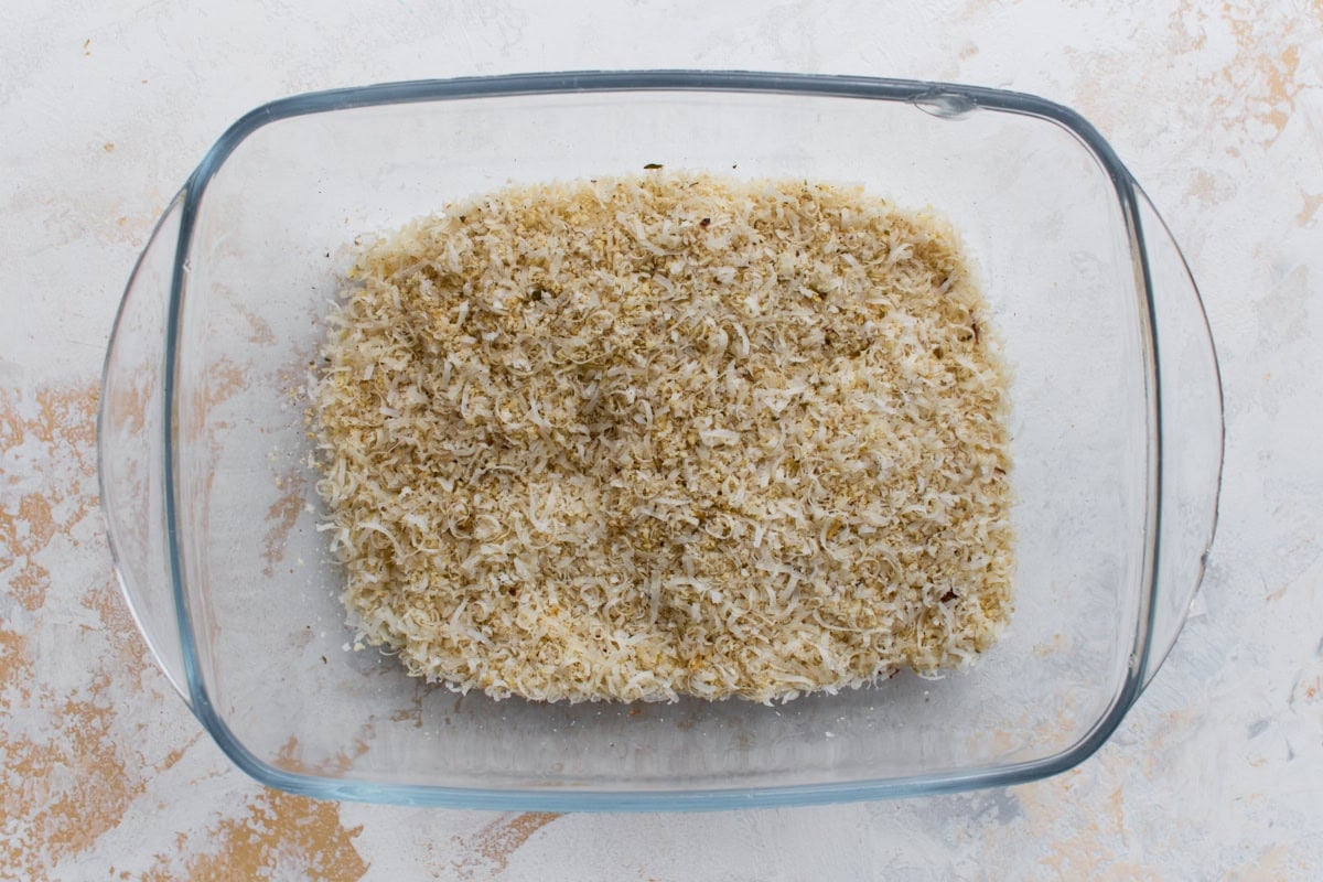 Parmesan, almond flour, and seasoning mixture in a glass dish for breading keto zucchini fries.