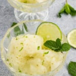 Lime sorbet scoops garnished with fresh mint and lime slices in glass dessert bowls.