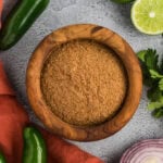 homemade gluten-free taco seasoning in a wooden bowl with jalapeños, lime, cilantro, and red onion