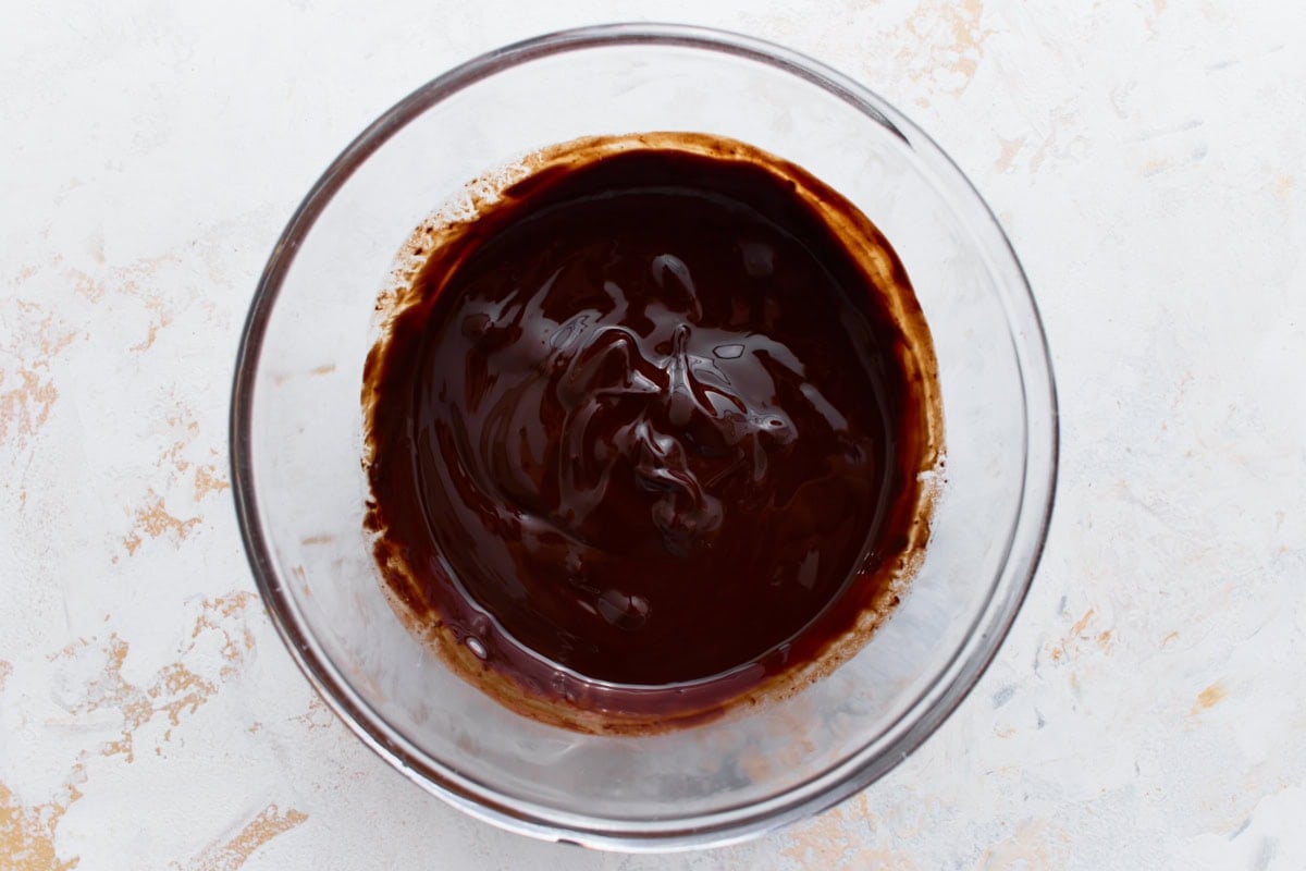 Melted dark chocolate and butter in a glass bowl, smooth and glossy, for flourless chocolate cookies.