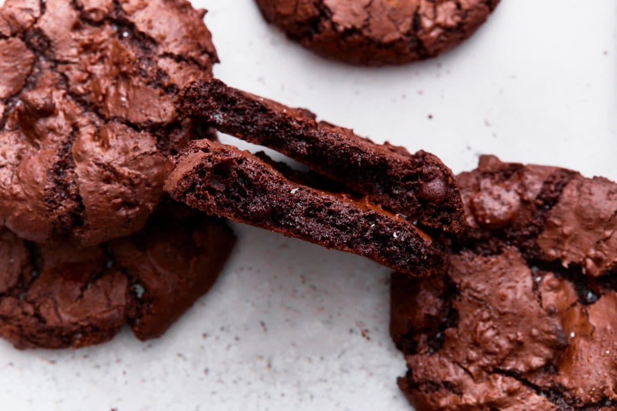 A flourless chocolate cookie split open to show the soft, fudgy interior and melted chocolate chips.