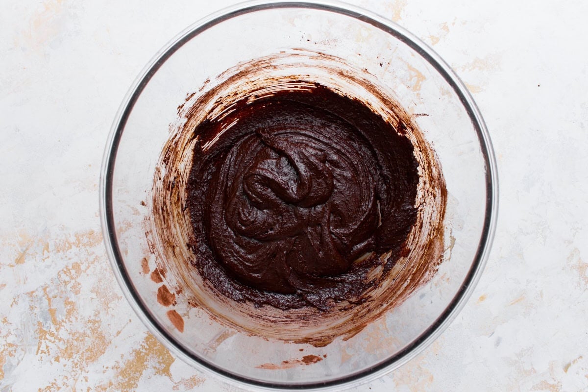 Thick, shiny flourless chocolate cookie dough after the cocoa powder, baking powder, and salt are stirred in.