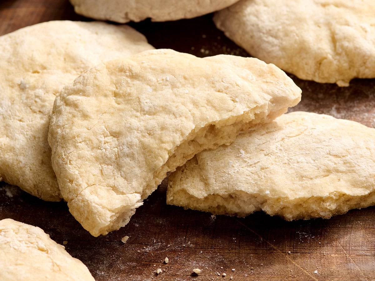 Baked gluten free pita bread torn open to show the fluffy interior and pocket.