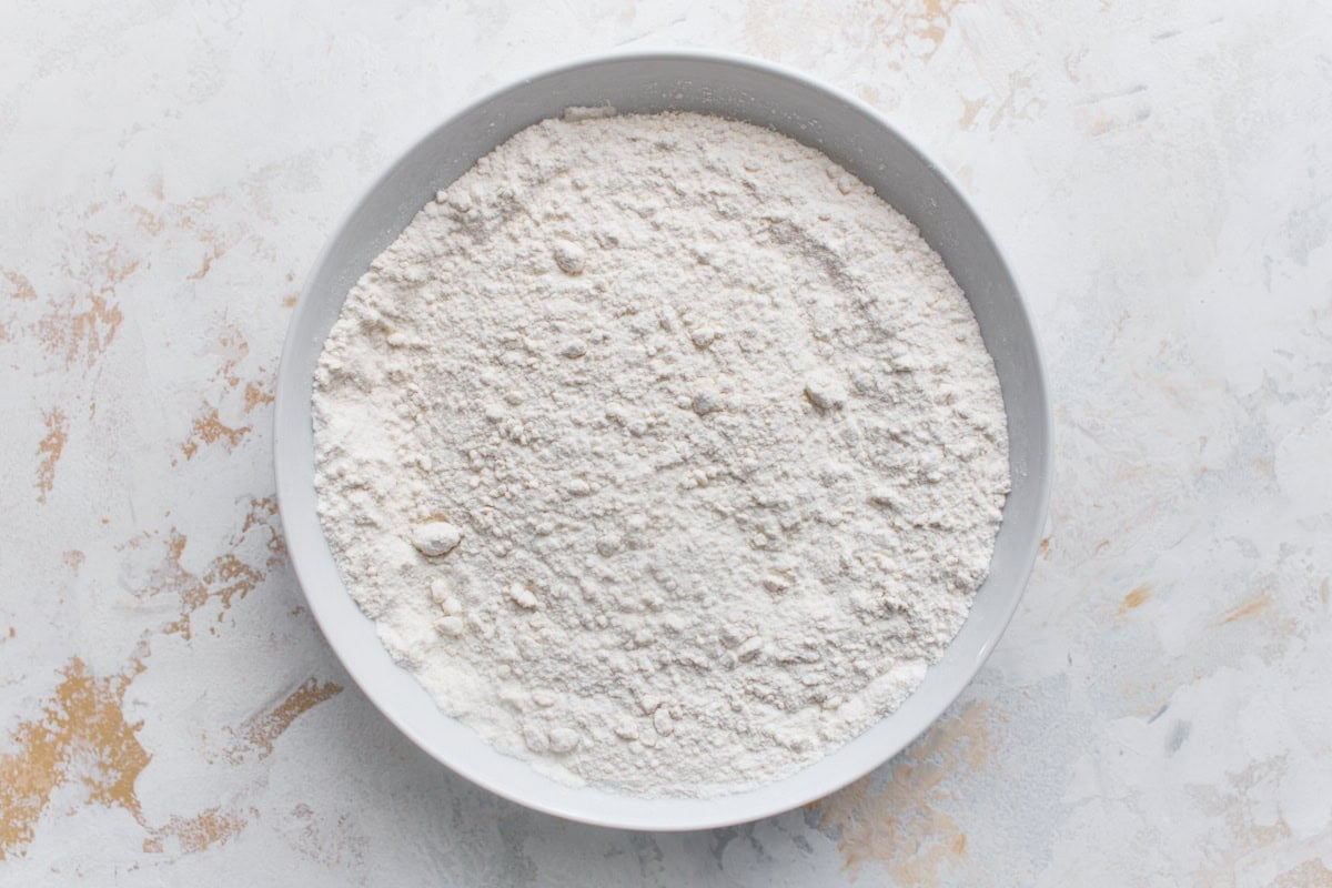 Gluten-free flour, baking powder, and salt whisked together in a white mixing bowl