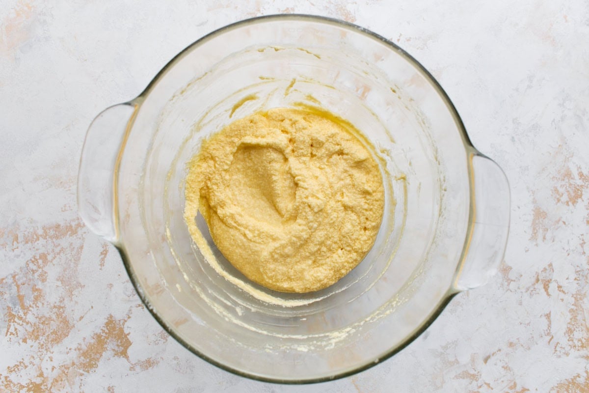 Cake batter in a glass bowl looking slightly curdled after the eggs are beaten in