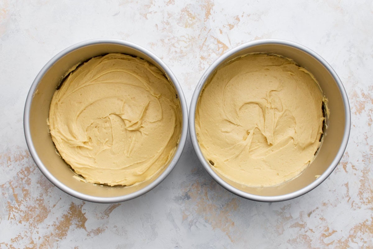 Cake batter divided evenly between two round cake pans with smoothed tops