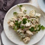 Keto chicken salad on a white plate garnished with fresh parsley, with a purple napkin and second plate in the background.