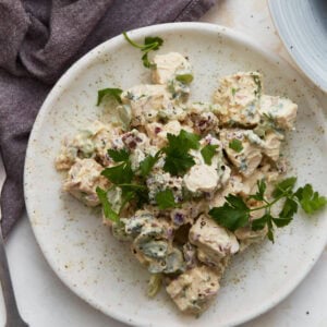 Keto chicken salad on a white plate garnished with fresh parsley, with a purple napkin and second plate in the background.