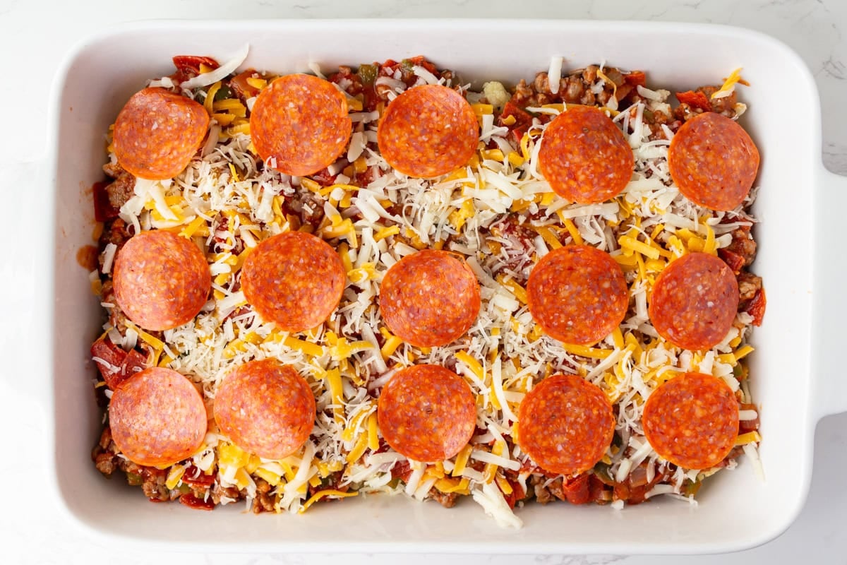 Unbaked keto pizza casserole topped with rows of whole pepperoni before going into the oven.