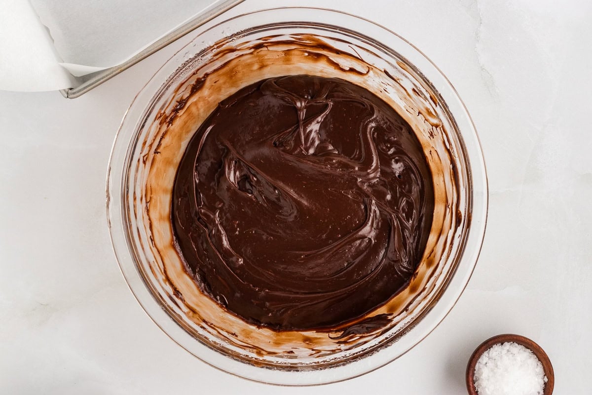 Overhead view of dairy-free chocolate fudge mixture partially melted and swirled in a glass bowl