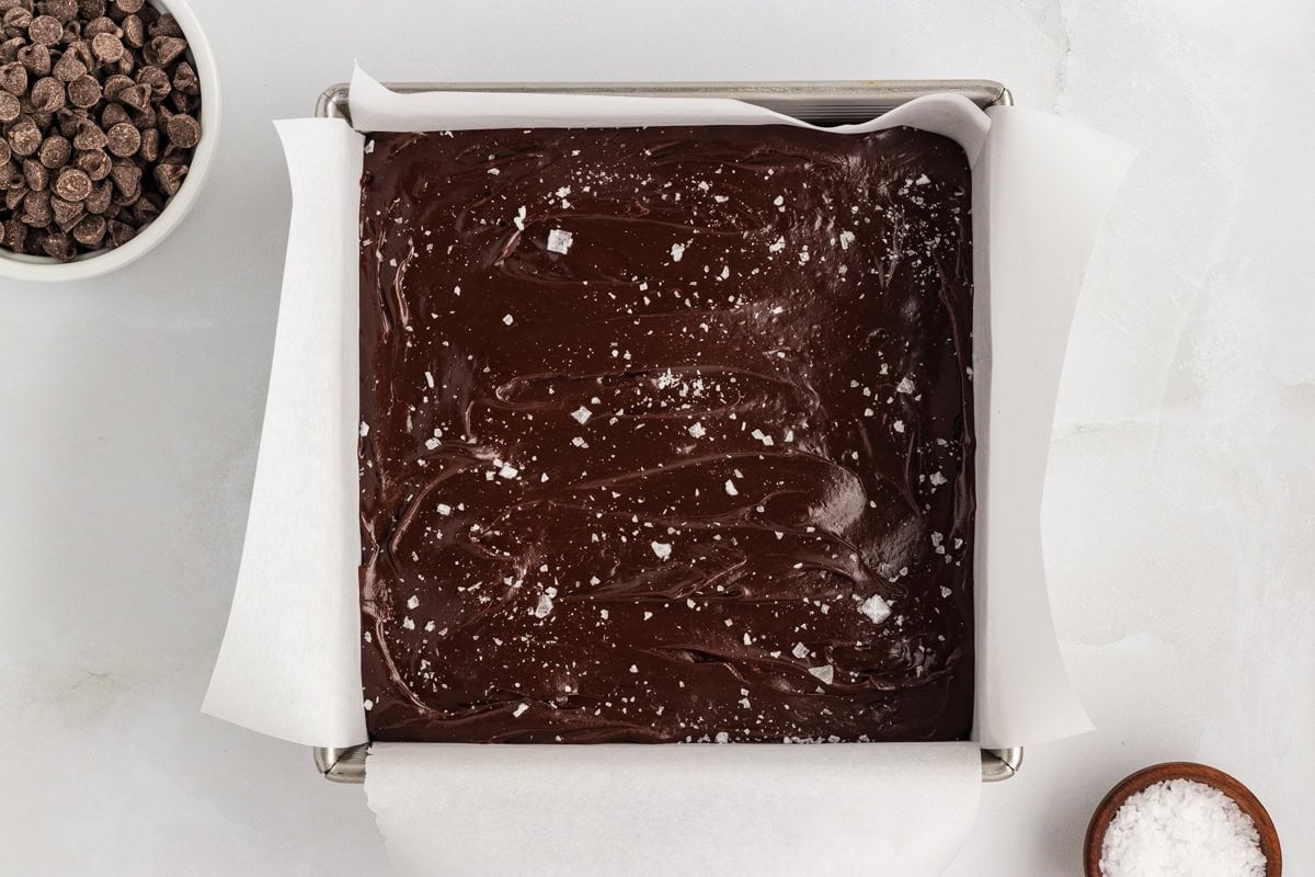 Gluten-free dairy-free chocolate fudge spread into a parchment-lined pan and topped with flaky sea salt