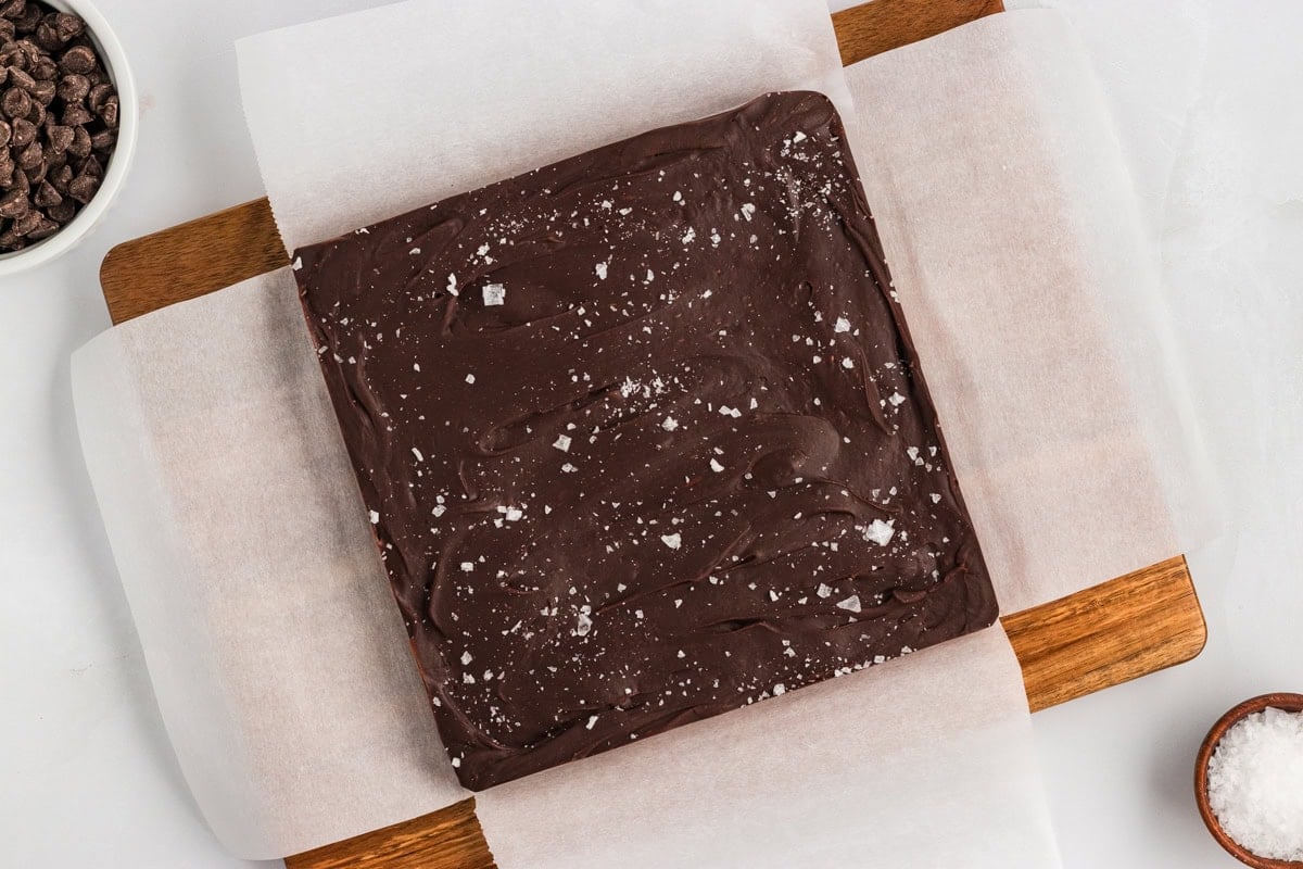 Set chocolate fudge lifted out of the pan on parchment paper and placed on a wood cutting board