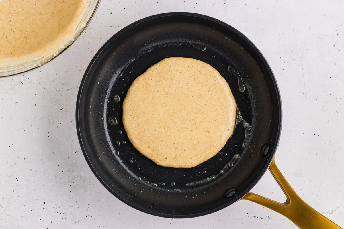Oat flour pancake batter poured into a hot skillet.