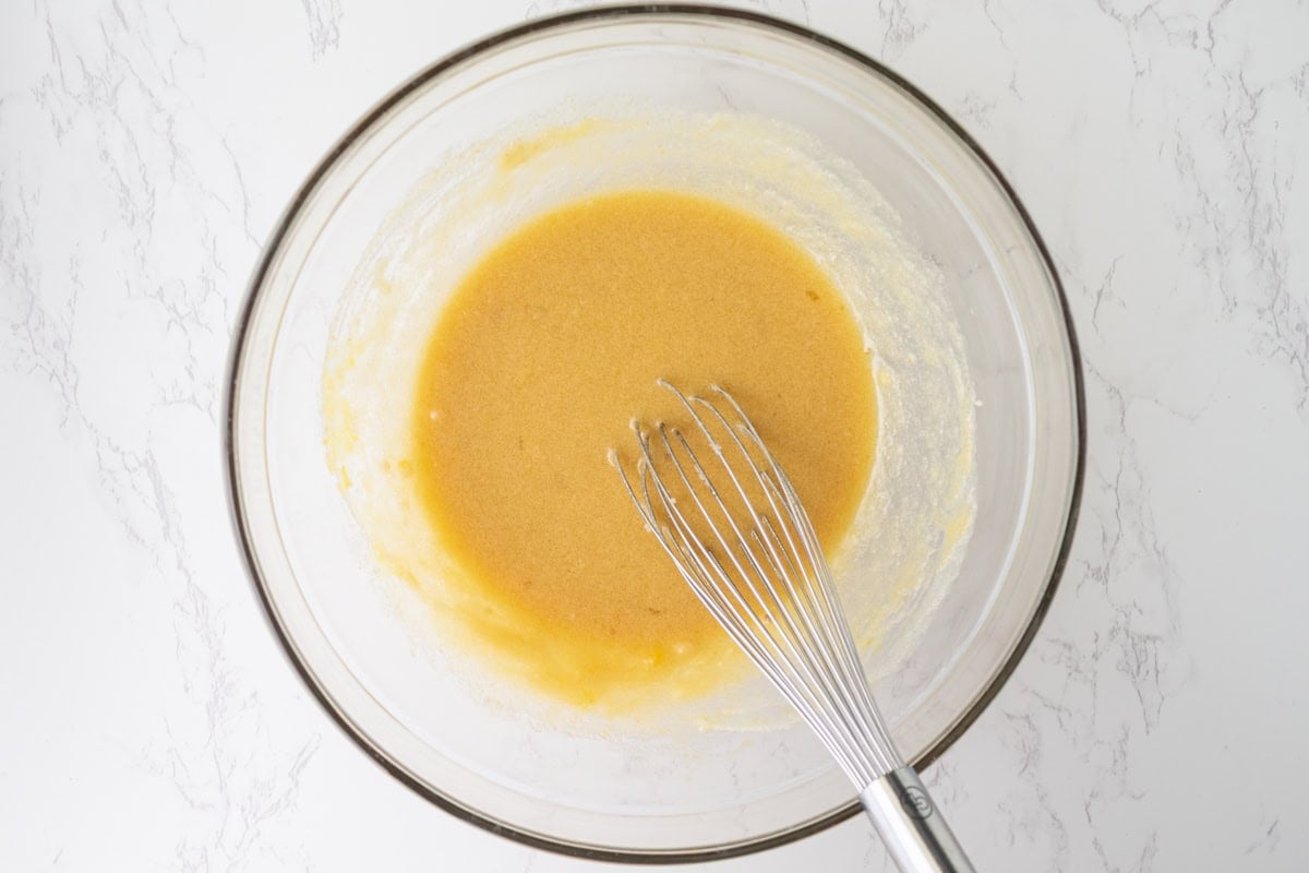 Eggs, corn syrup, and vanilla whisked into the butter and sugar mixture until glossy in a glass mixing bowl.