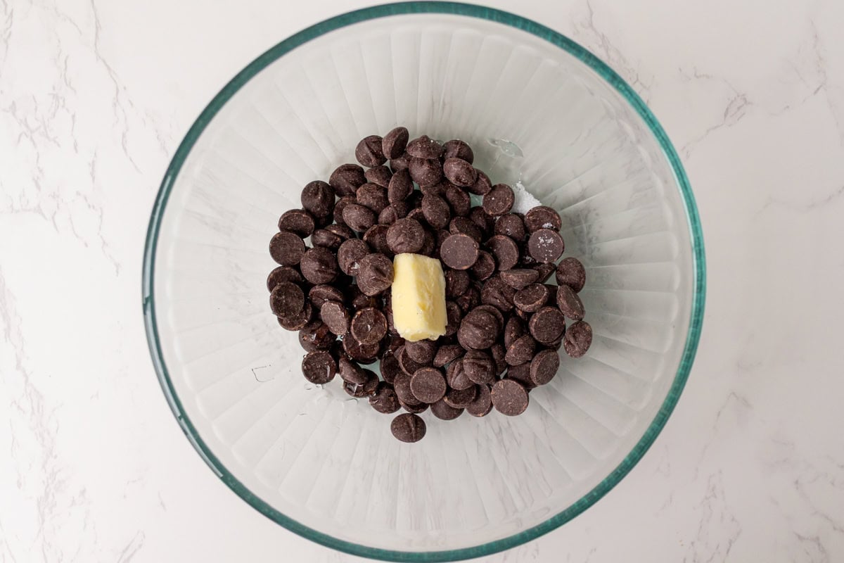 Chopped bittersweet chocolate and butter in a glass bowl, ready for hot cream to be poured over for the ganache.