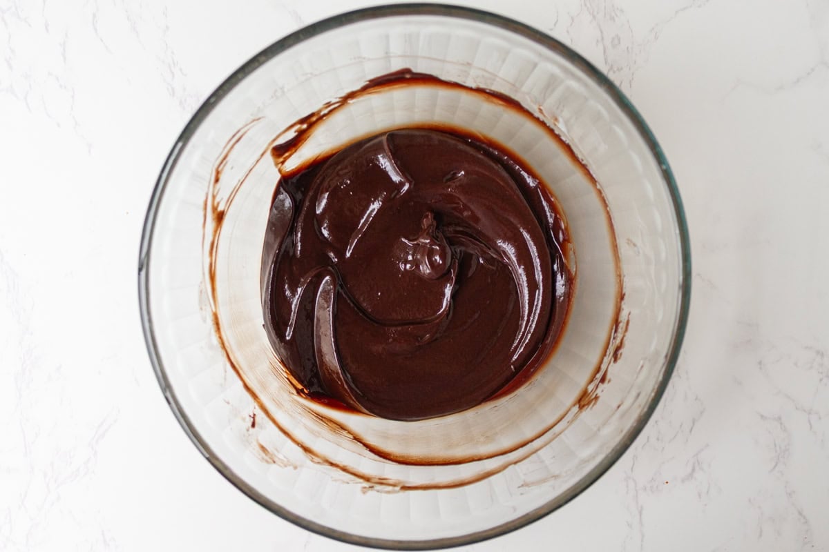 Smooth, glossy chocolate ganache in a glass bowl after melting and stirring.