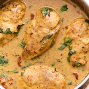 Overhead close-up of dairy-free Marry Me Chicken in a skillet, coated in a creamy sun-dried tomato sauce and topped with fresh basil.