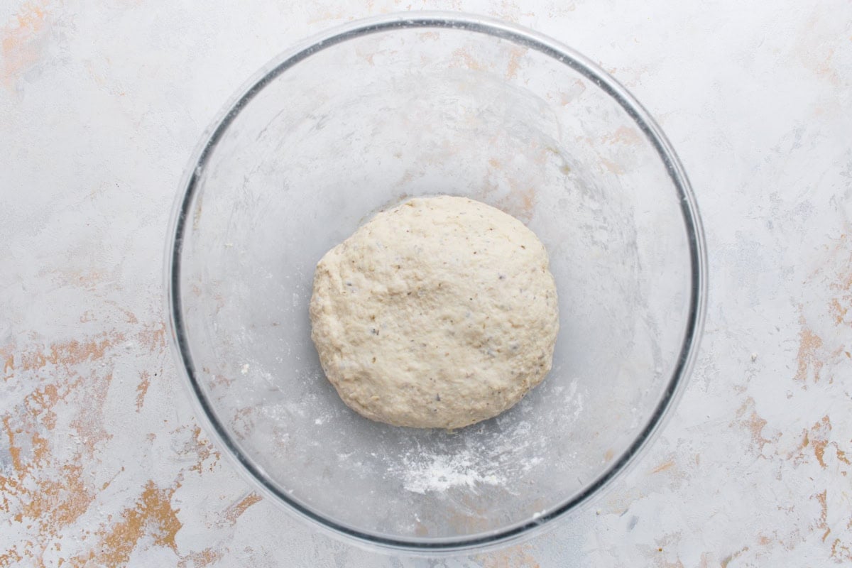 Gluten-free flatbread dough formed into a soft ball in a glass mixing bowl.