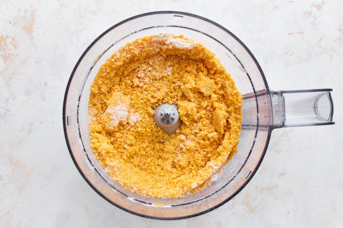 Gluten-free flour, shredded cheddar, and butter pulsed into a crumbly, sand-like texture in a food processor.