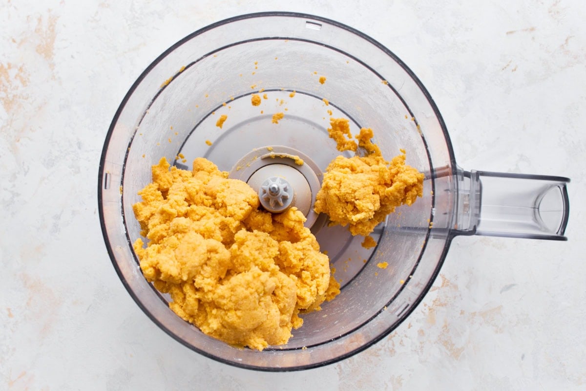 Gluten-free goldfish cracker dough clumped together in a food processor after adding cold water.