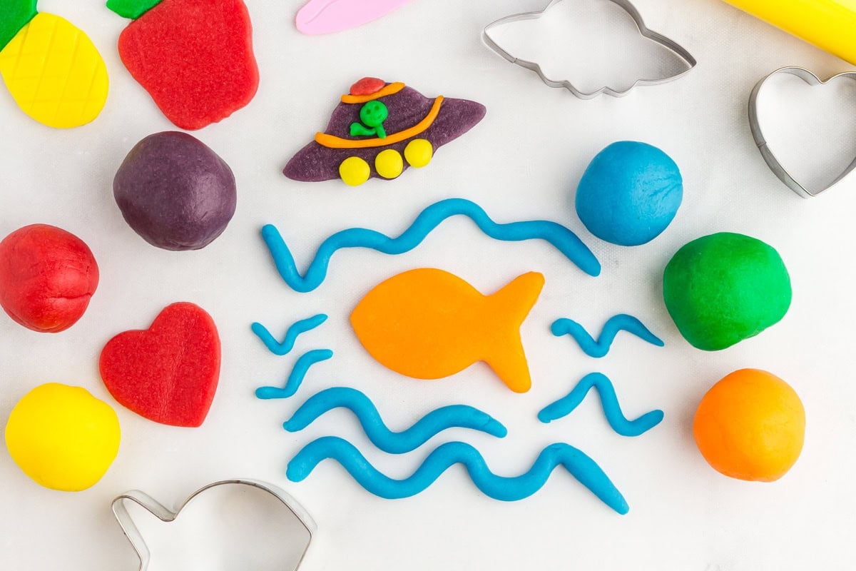 a pineapple, strawberry, heart, fish, waves, and a UFO scene made from colored play doh