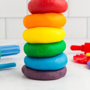 red, orange, yellow, green, blue, and purple play doh stacked on a kitchen counter
