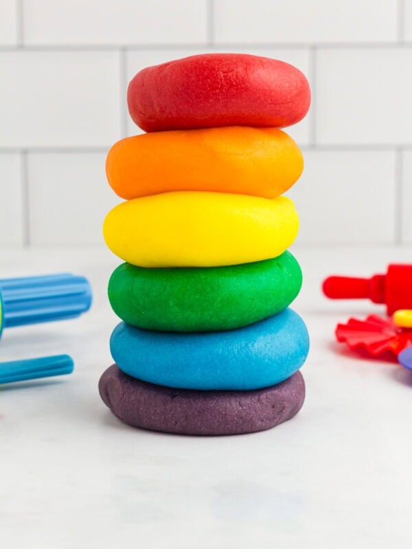 red, orange, yellow, green, blue, and purple play doh stacked on a kitchen counter