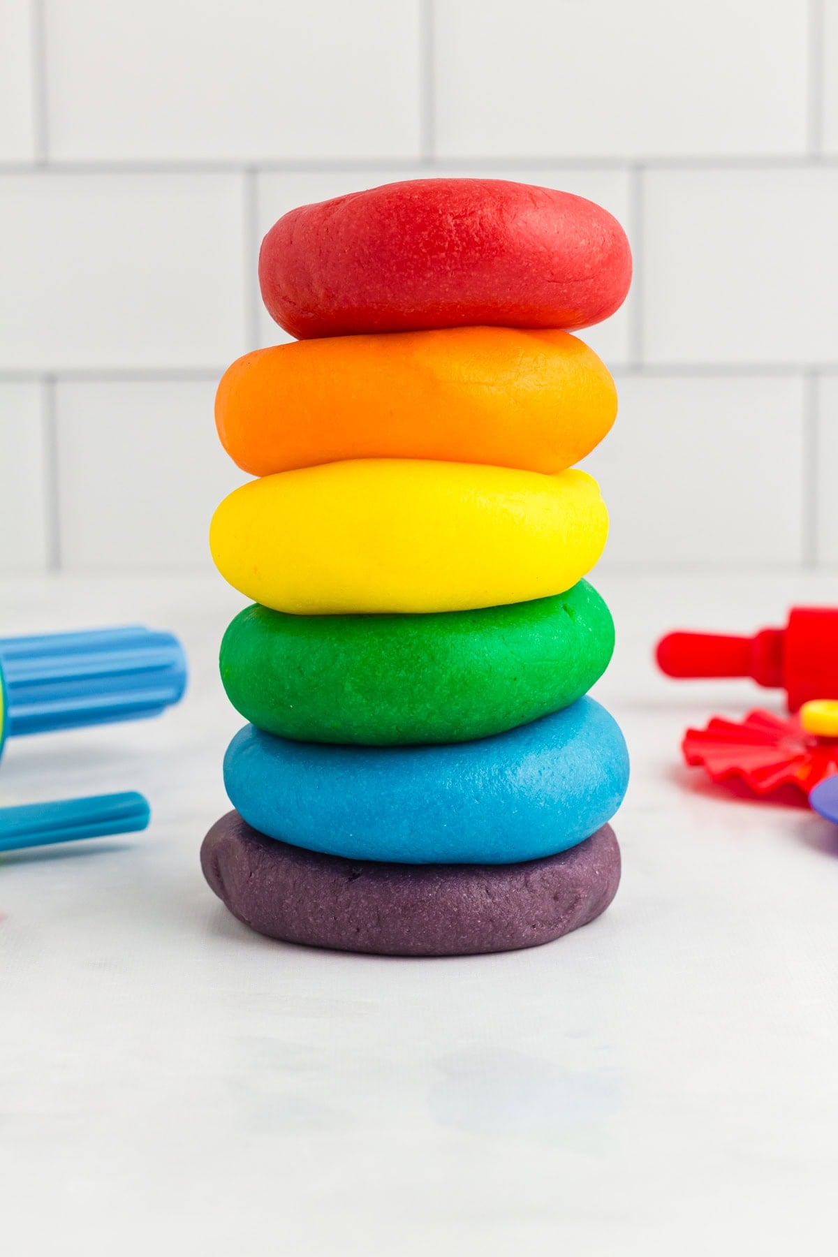 red, orange, yellow, green, blue, and purple play doh stacked on a kitchen counter