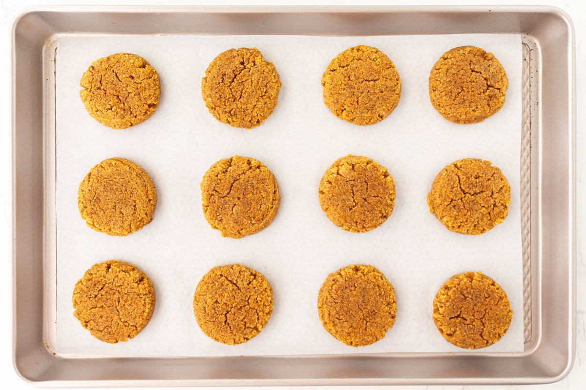 Baked gluten-free almond flour pumpkin cookies cooling on a parchment-lined baking sheet.