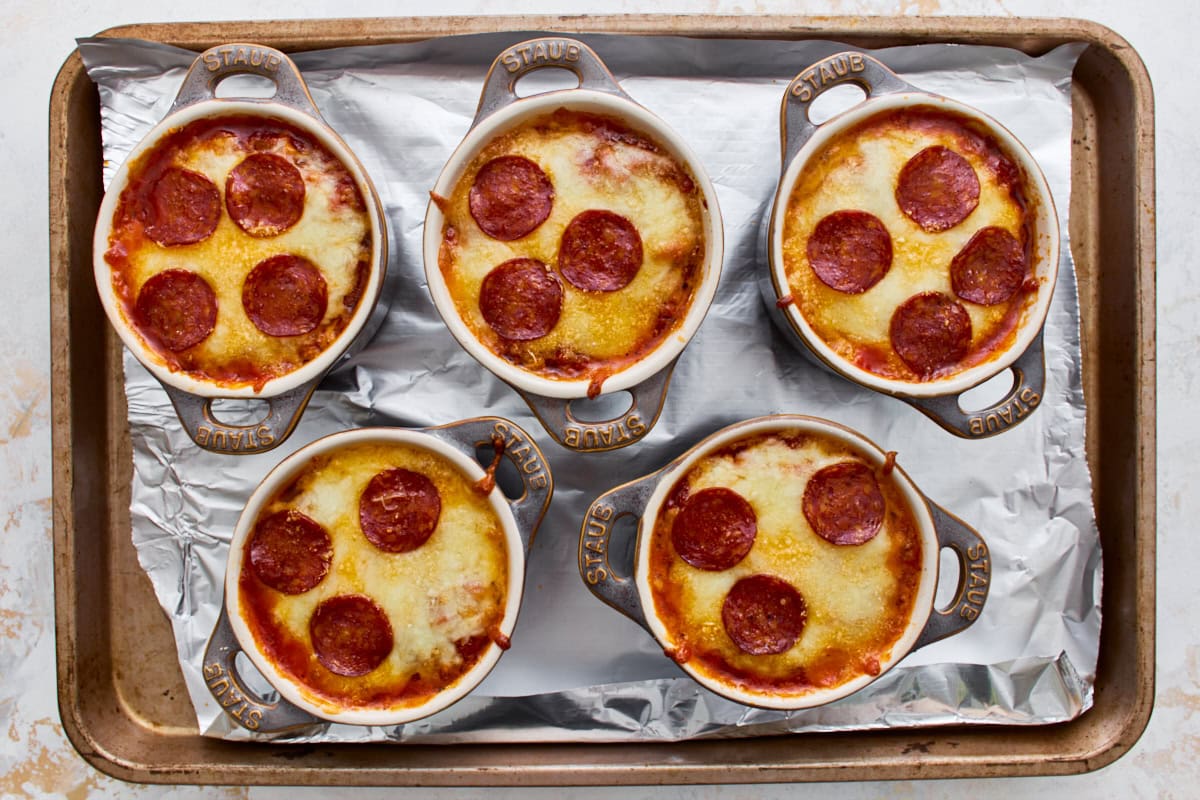 Five gluten-free crustless pizza bowls with melted, bubbly cheese on a baking sheet.