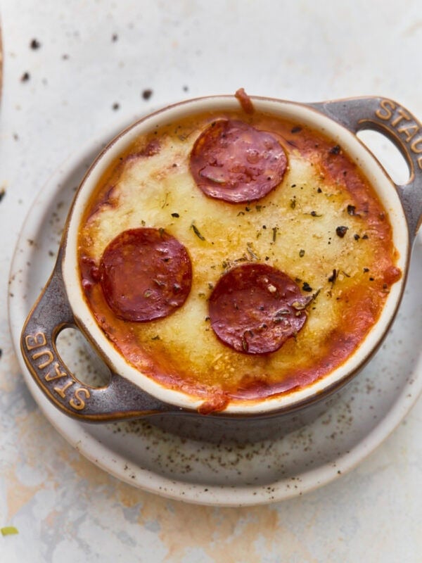 Overhead view of a gluten-free crustless pizza bowl with melted mozzarella, Parmesan, and pepperoni in a mini cast iron cocotte.